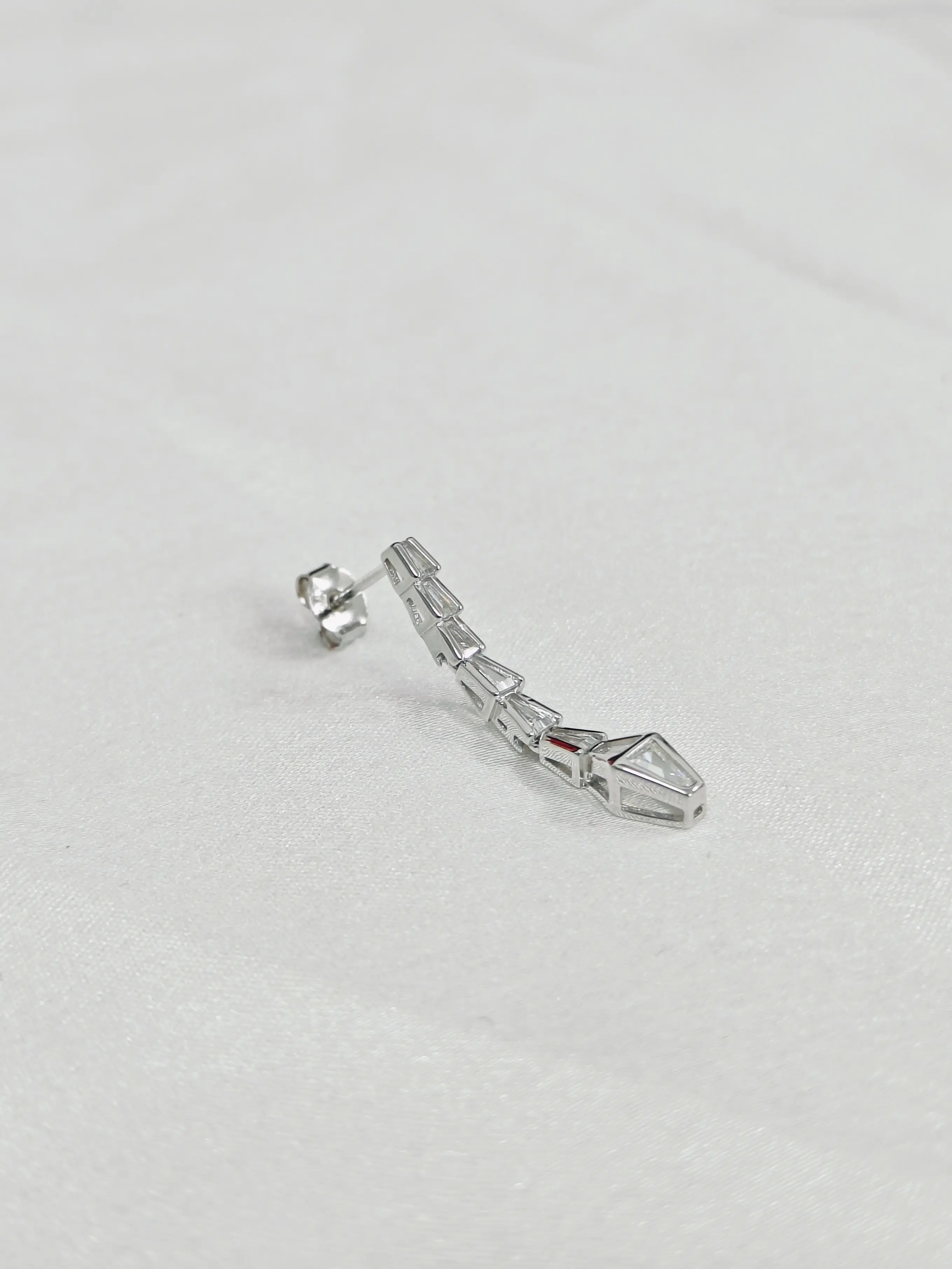 Silver earring on a light gray background